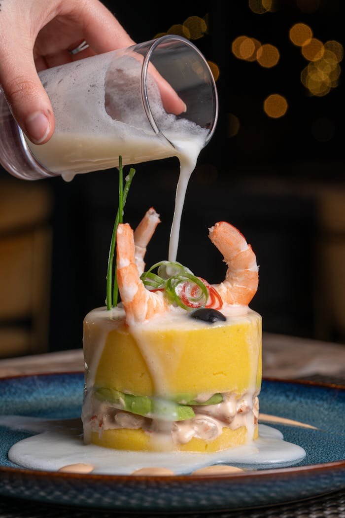 gallery-06 Delicious Peruvian causa with shrimp, avocado, and sauce for a gourmet experience.